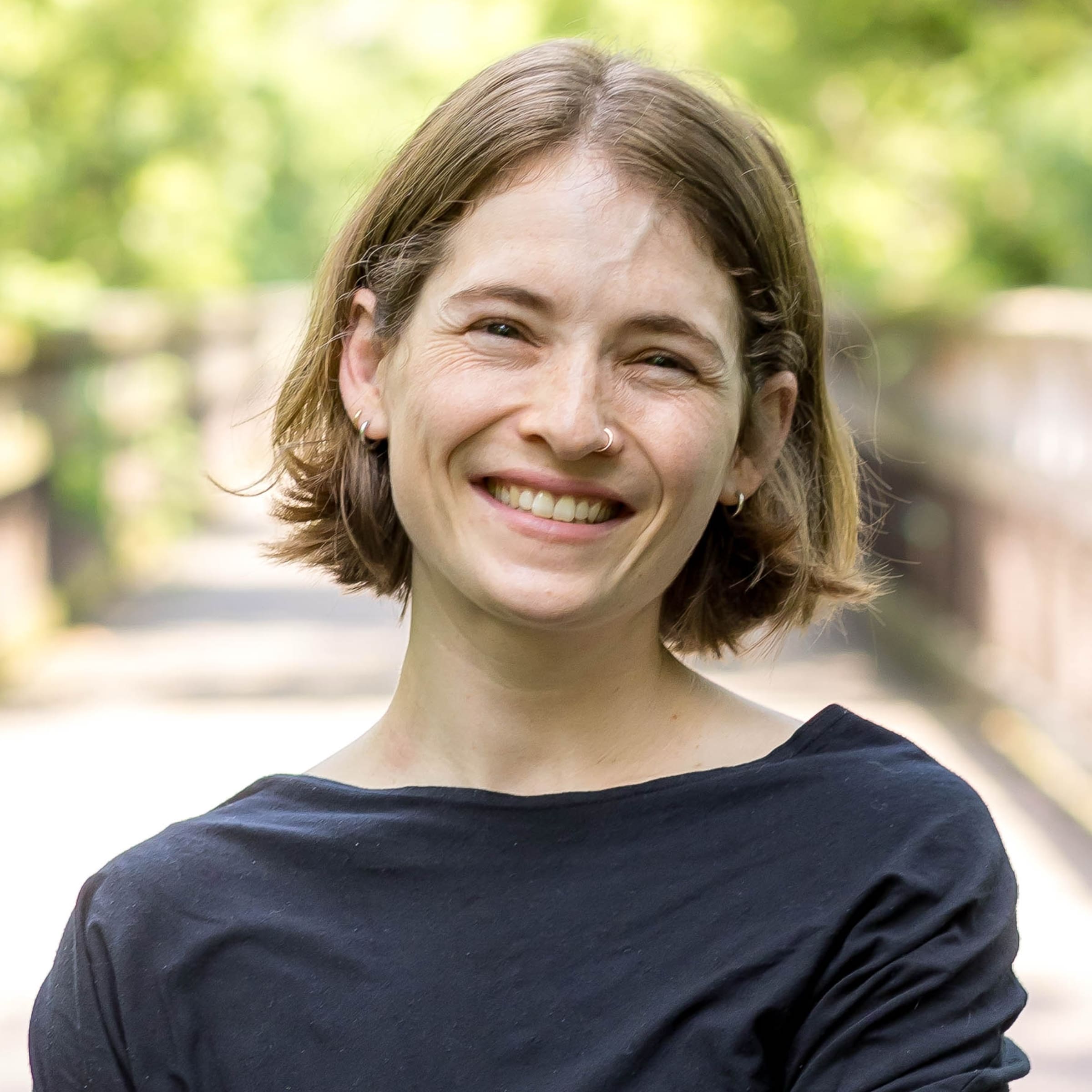 Allison Beer, practitioner at The Resiliency Center of Greater Philadelphia, smiling outdoors in front of a soft-focus green park background.