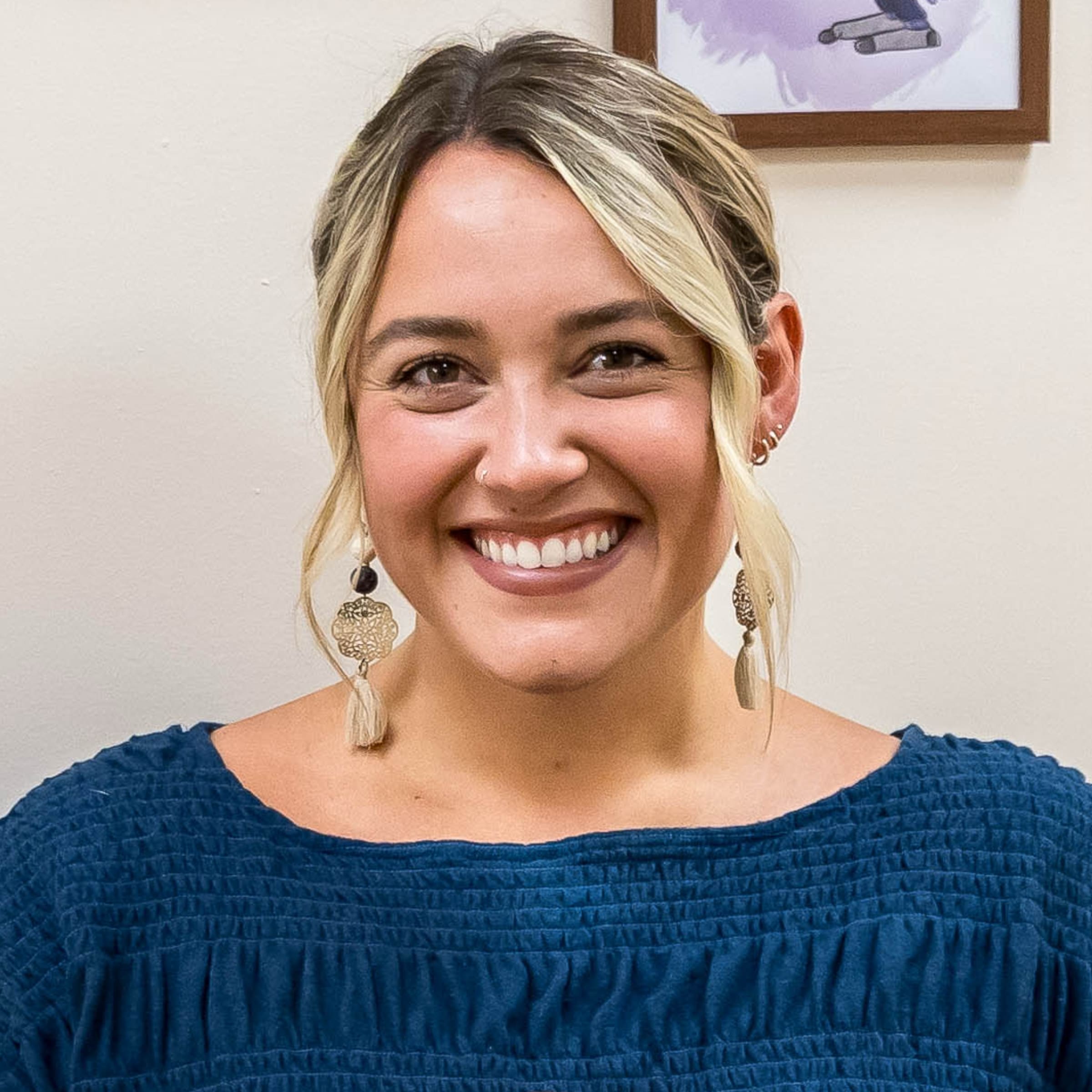Julia Weimer, practitioner at The Resiliency Center of Greater Philadelphia, smiling indoors against a light wall with framed artwork.