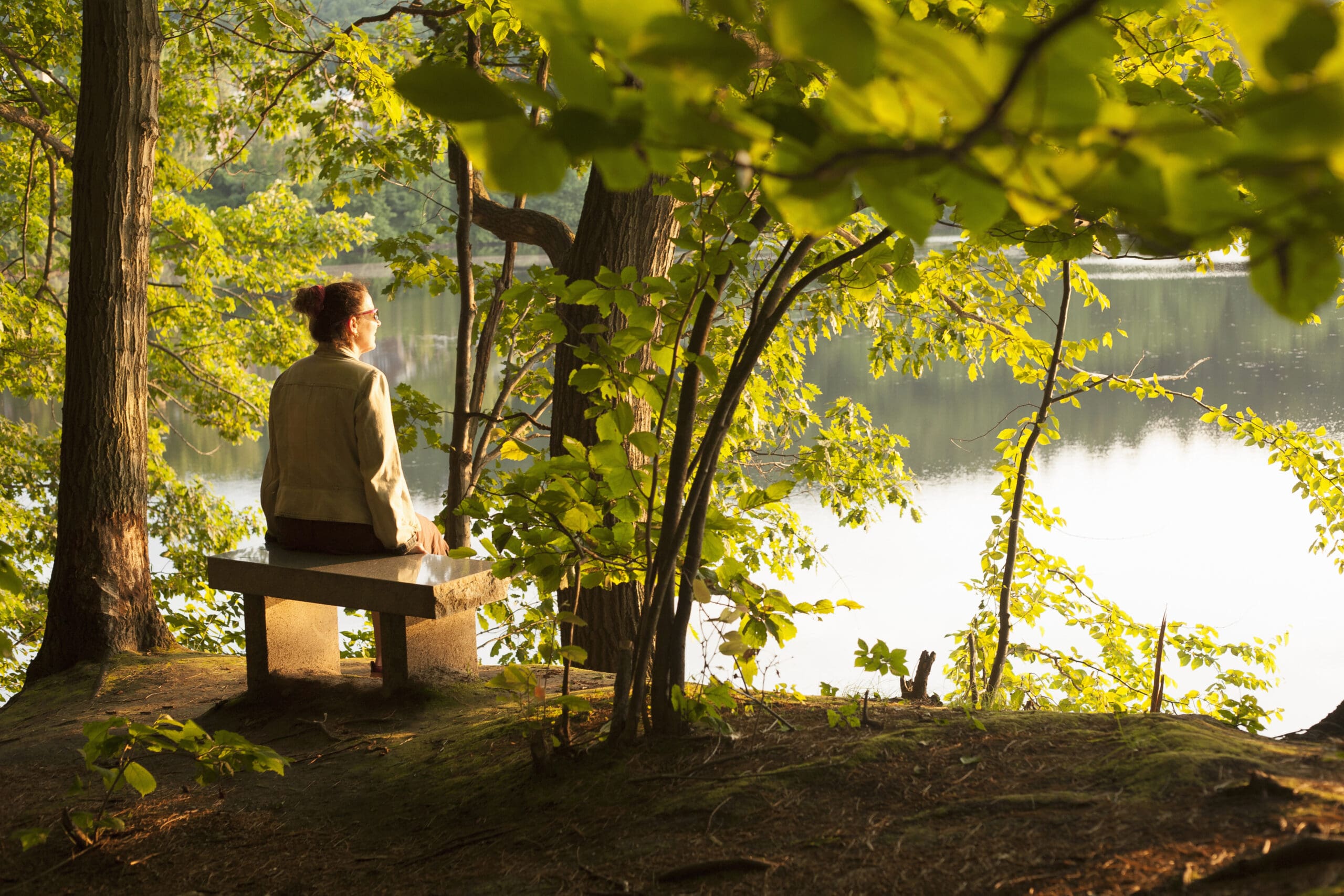 Mature woman sitting on lakeside seat