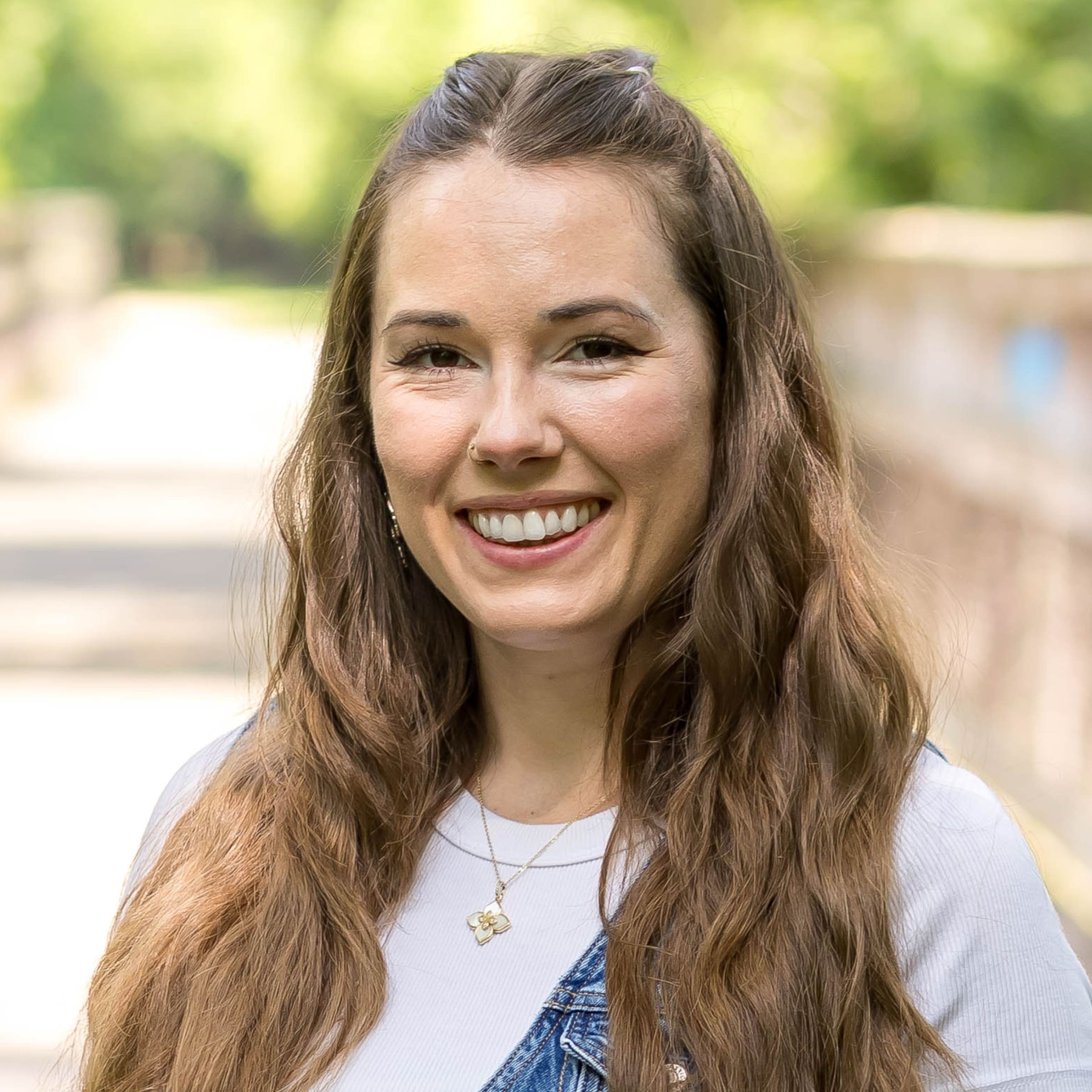 Savannah Aykol, practitioner at The Resiliency Center of Greater Philadelphia, smiling outdoors in front of a soft-focus green park background.
