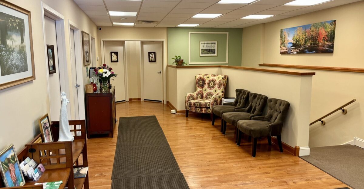 Waiting area with chairs, green accent wall, artwork, and a staircase railing.