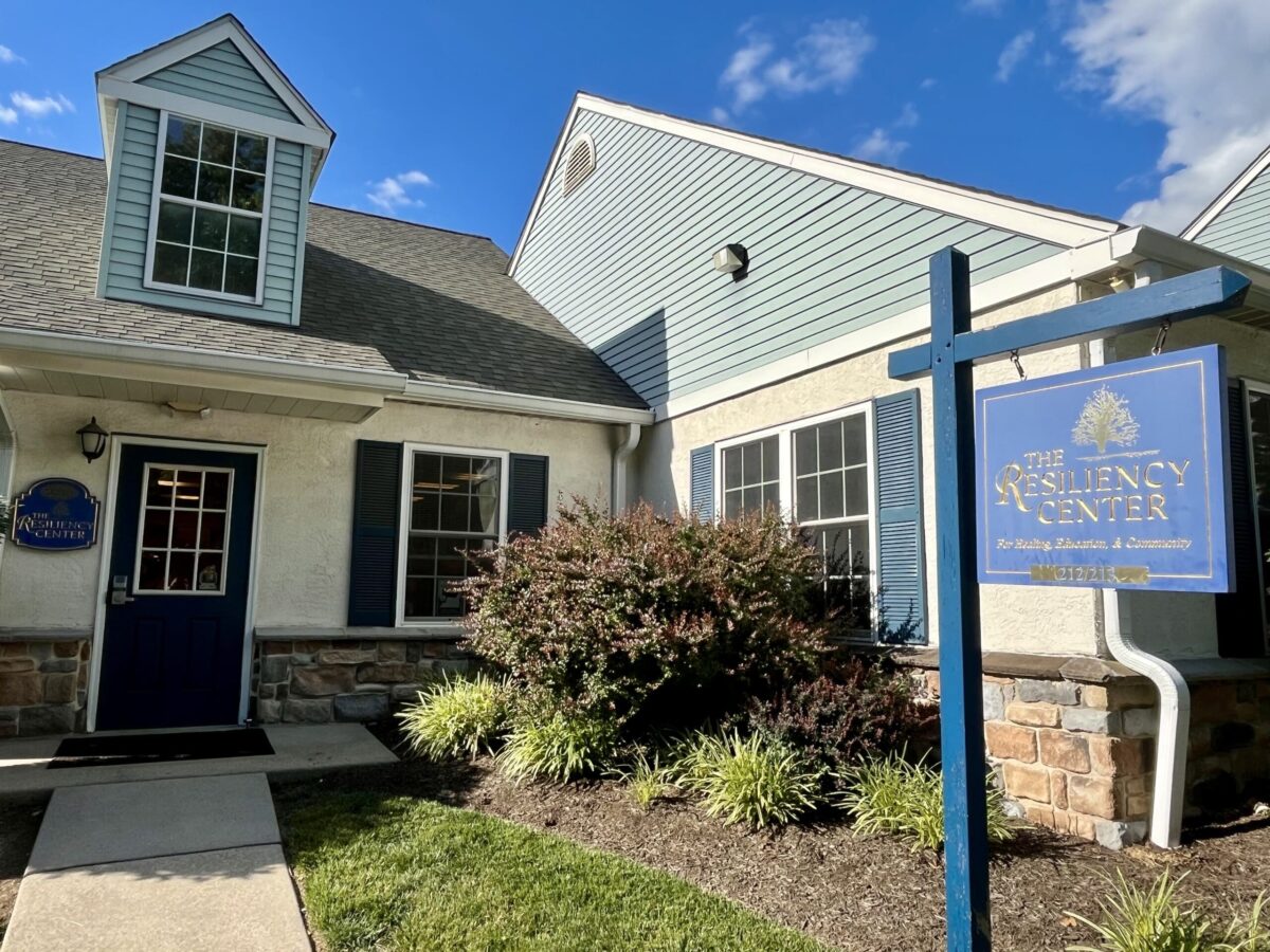 Blue two-story building with light blue siding, gabled dormer, and a sign for The Resiliency Center.