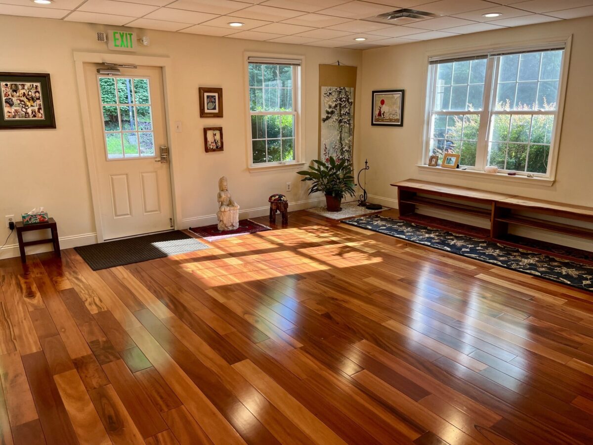 Bright entrance room with wooden floors, large windows, exit door, and wall art.