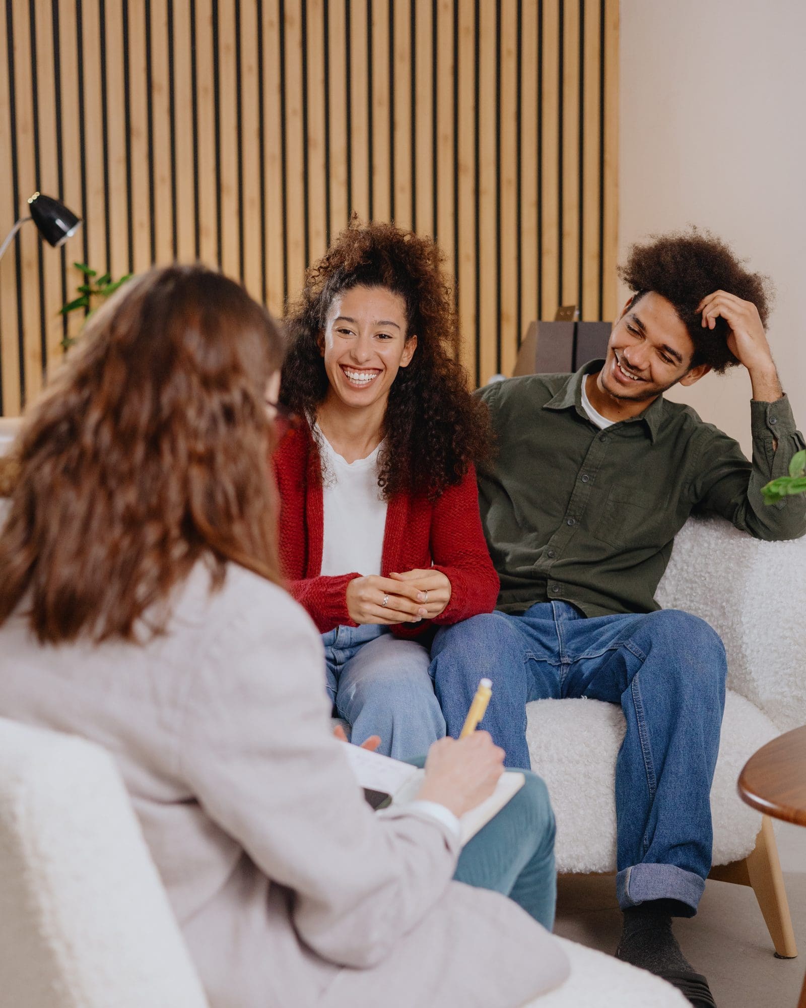 A couple sitting on a couch, laughing with their therapist during a counseling session