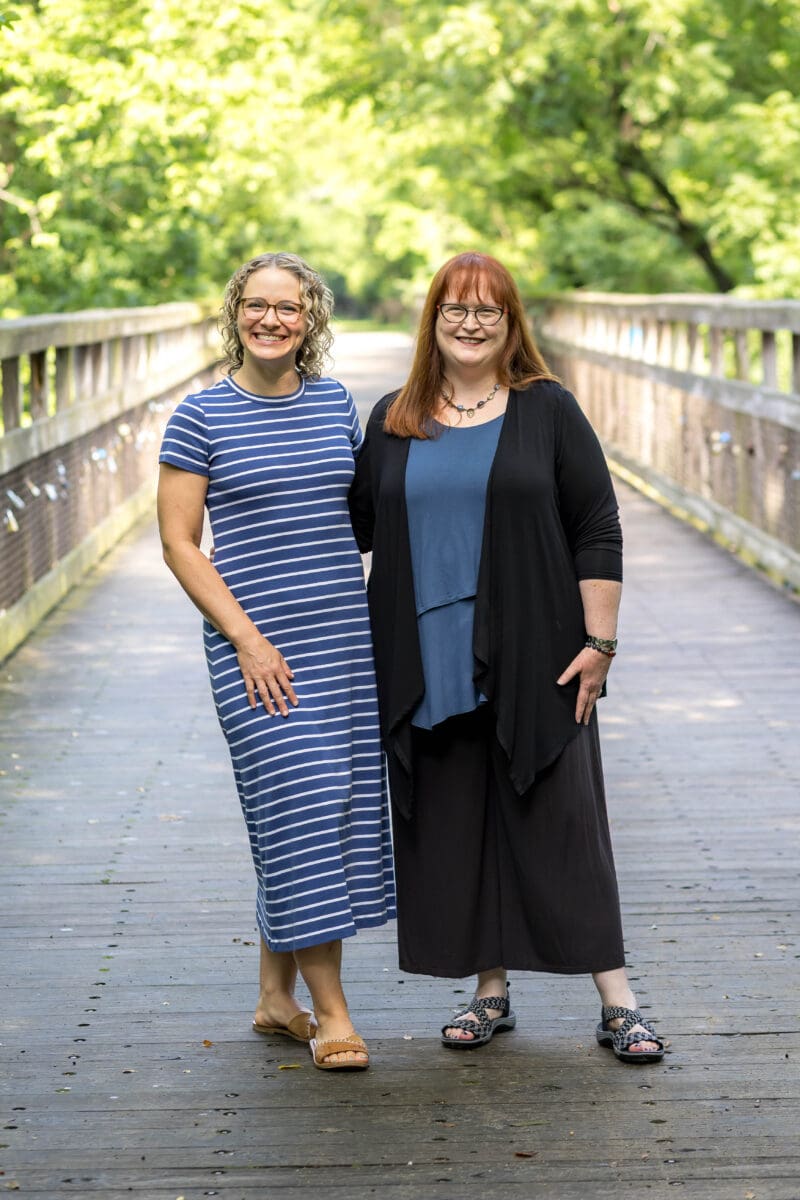 Elizabeth Venart and Elizabeth Campbell standing together on a wooden footbridge